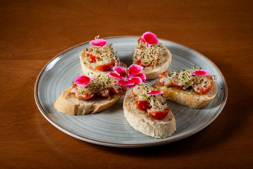 Bruschettas gourmet decoradas com flores comestíveis no Bistrô Mini Mundo, parte do cardápio temático da Copa.