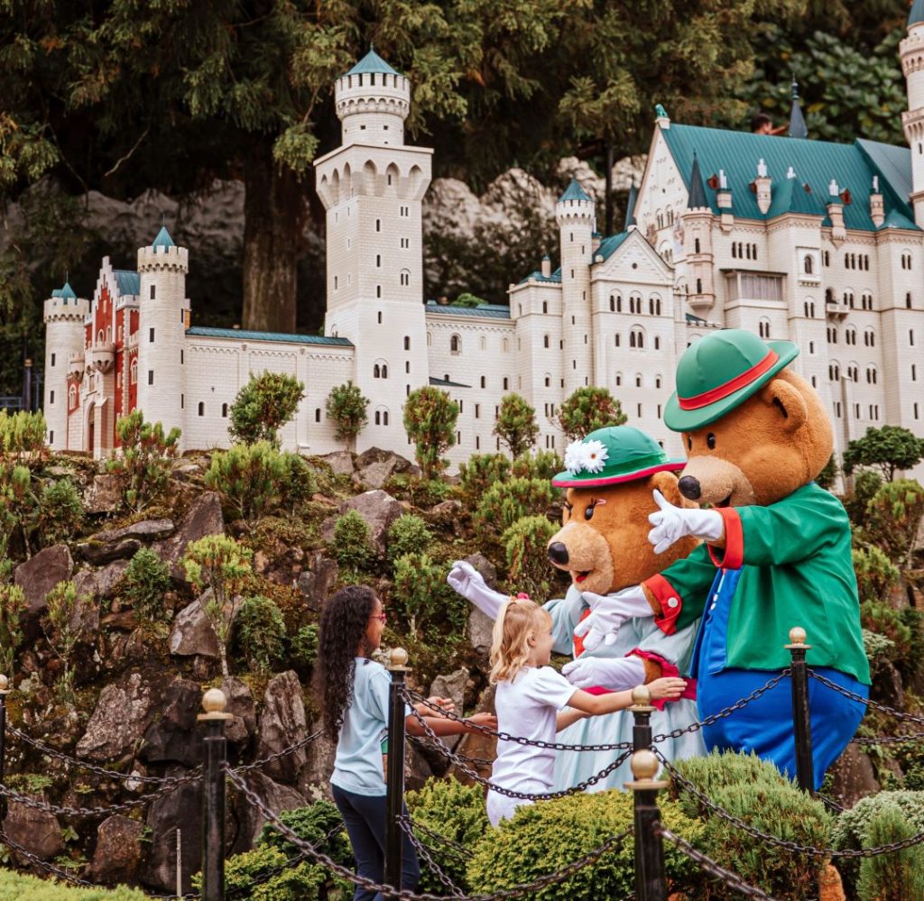 Criança e personagens do Mini Mundo para todas as idades em frente ao castelo em miniatura